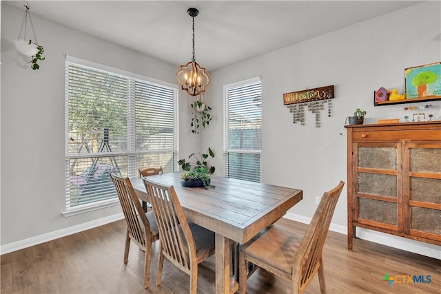 dining space with baseboards, wood finished floors, and a chandelier