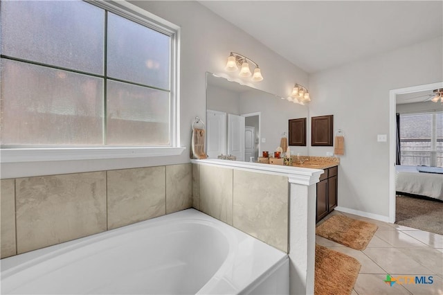 full bath featuring ensuite bath, tile patterned flooring, baseboards, a bath, and vanity