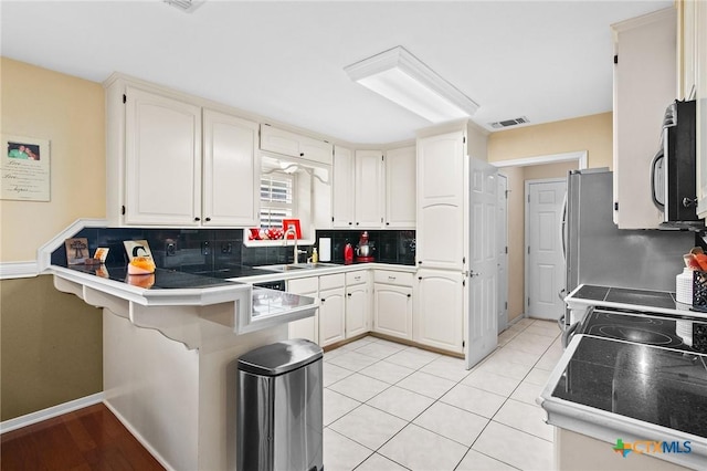308 Green Gable Dr, Victoria, TX 77904 - kitchen featuring appliances with stainless steel finishes, a peninsula, decorative backsplash, a breakfast bar area, and a sink