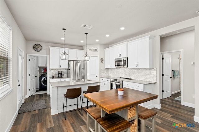 964 Allende St, Seguin, TX 78155 - kitchen with appliances with stainless steel finishes, washer / clothes dryer, a sink, tasteful backsplash, and a kitchen island with sink