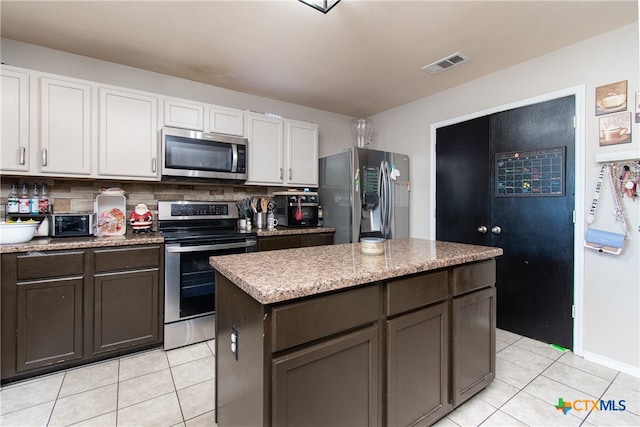 kitchen with white cabinetry, a center island, light tile patterned floors, and appliances with stainless steel finishes