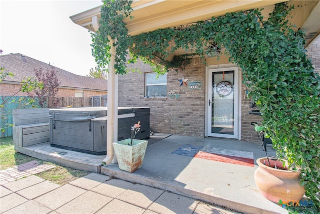 doorway to property with a patio and a hot tub