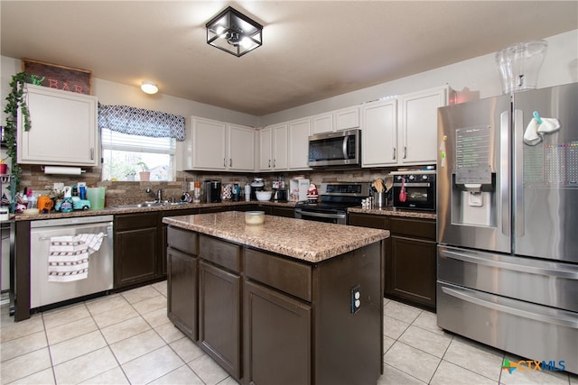 kitchen featuring dark brown cabinetry, white cabinets, light tile patterned flooring, a kitchen island, and appliances with stainless steel finishes