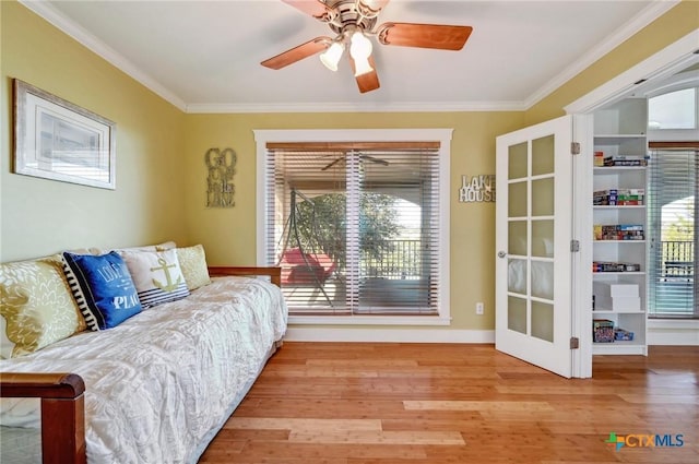 sitting room featuring a wealth of natural light, wood finished floors, ceiling fan, and ornamental molding