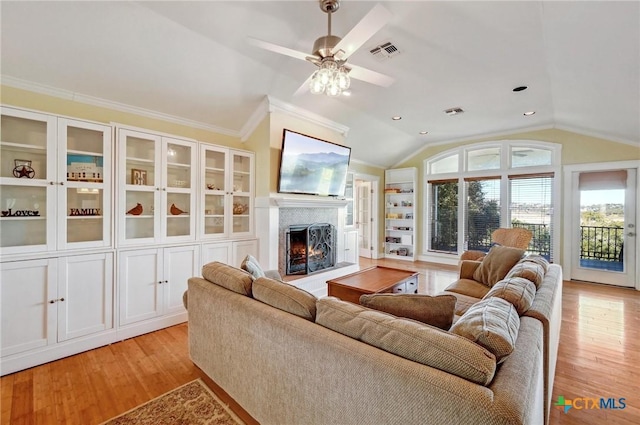 living area with visible vents, light wood-style flooring, a ceiling fan, a high end fireplace, and lofted ceiling