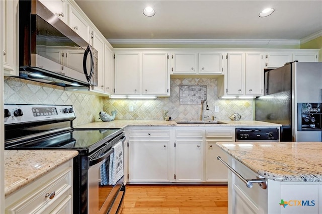 kitchen with a sink, appliances with stainless steel finishes, ornamental molding, and white cabinetry