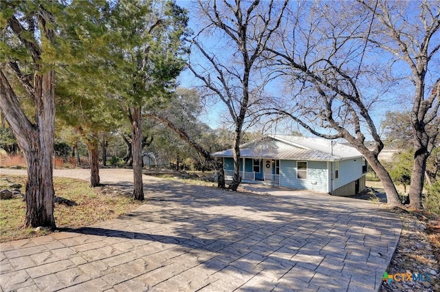 ranch-style home with a porch, metal roof, and decorative driveway