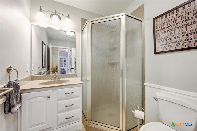 bathroom with a shower stall, vanity, and toilet