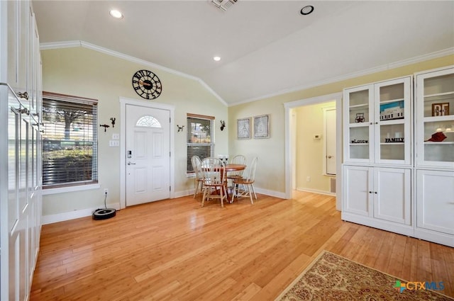 entrance foyer featuring lofted ceiling, ornamental molding, and light wood finished floors