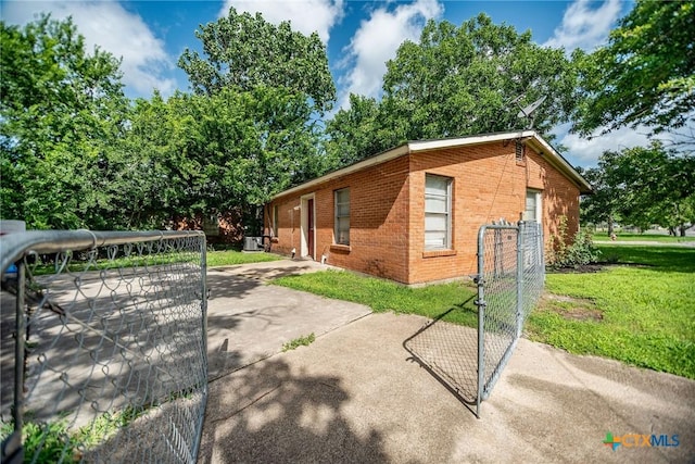 2102 Leon Dr, Port Lavaca, TX 77979 - view of side of home featuring brick siding, a gate, and a lawn