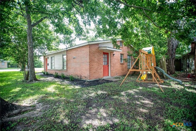 2102 Leon Dr, Port Lavaca, TX 77979 - view of property exterior featuring brick siding, a playground, and a lawn