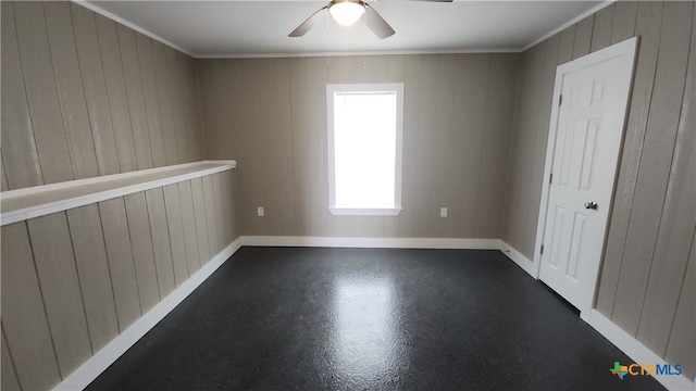 empty room featuring ornamental molding, wood walls, and ceiling fan