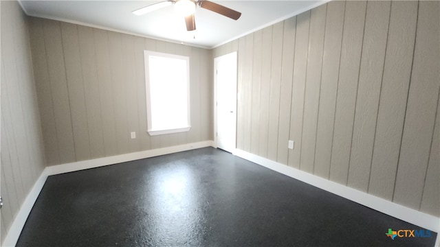 spare room featuring wood walls, ceiling fan, and crown molding