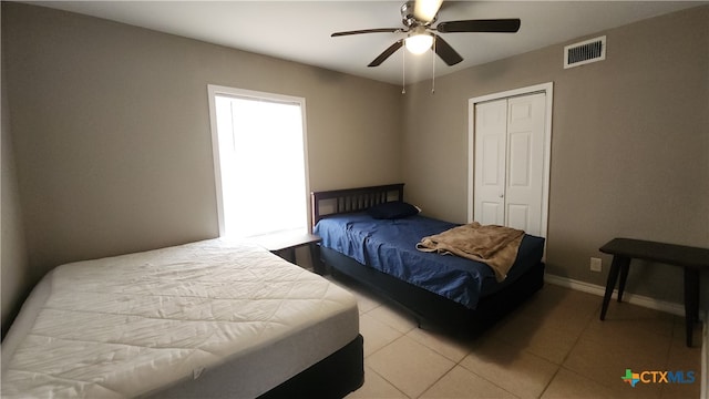 tiled bedroom with ceiling fan and a closet