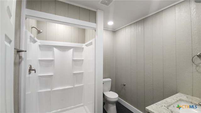 bathroom with walk in shower, wood walls, sink, and toilet