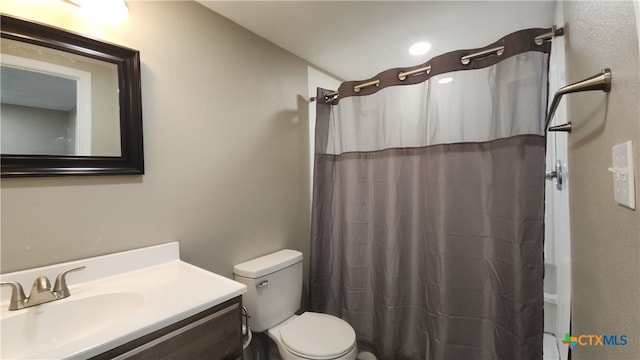 bathroom with toilet, vanity, and walk in shower