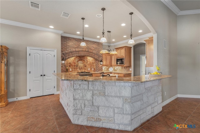 kitchen featuring stainless steel microwave, arched walkways, ornamental molding, and visible vents