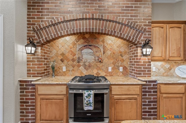 kitchen with stainless steel range with gas cooktop, light stone counters, and tasteful backsplash