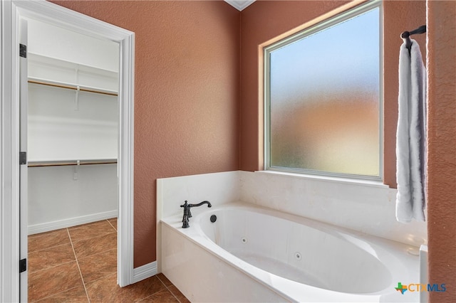 full bath featuring baseboards, a jetted tub, tile patterned flooring, and a walk in closet