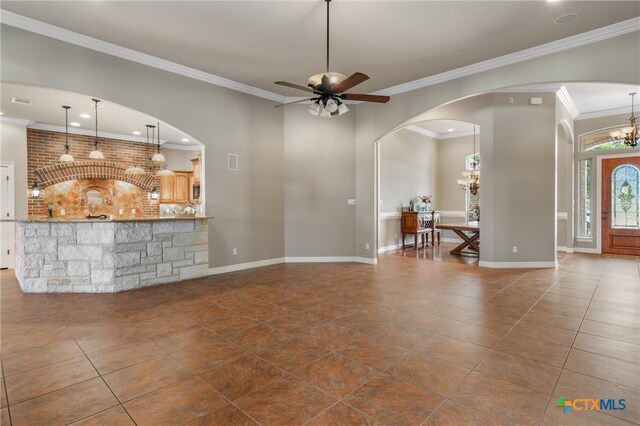 living room with arched walkways, crown molding, dark tile patterned floors, and ceiling fan with notable chandelier