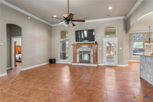 unfurnished living room with a ceiling fan, visible vents, a fireplace, and crown molding