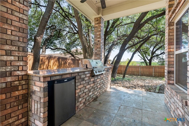 view of patio / terrace featuring a fenced backyard, an outdoor kitchen, ceiling fan, and area for grilling