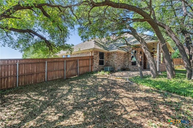 view of yard featuring a ceiling fan, central AC unit, and fence