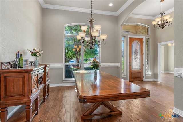 dining room with a notable chandelier, arched walkways, wood-type flooring, baseboards, and ornamental molding