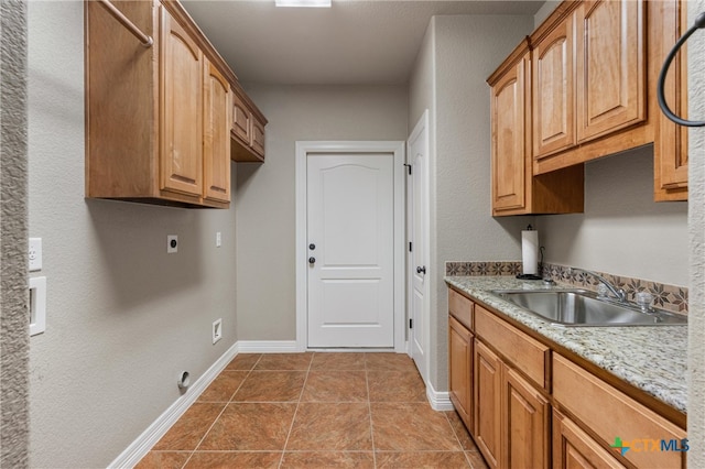 clothes washing area featuring hookup for an electric dryer, cabinet space, a sink, and baseboards