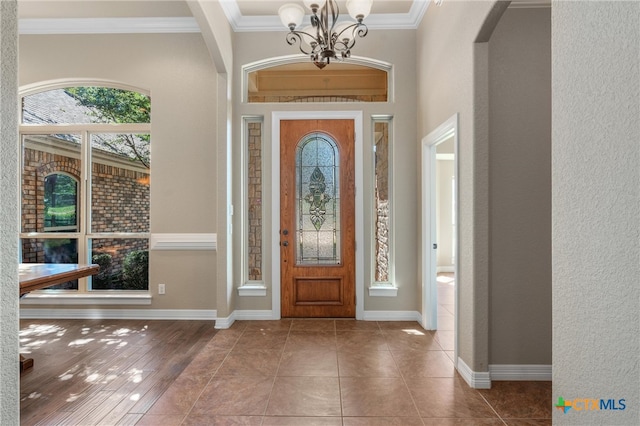 foyer entrance featuring ornamental molding, arched walkways, a healthy amount of sunlight, and a chandelier