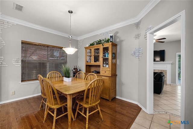 25039 Arrow Gln, San Antonio, TX 78258 - dining space with a ceiling fan, baseboards, ornamental molding, light wood-style flooring, and a tile fireplace