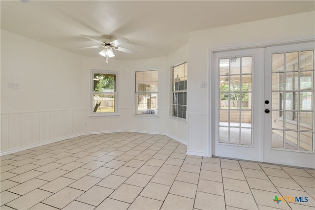 tiled empty room featuring french doors and ceiling fan