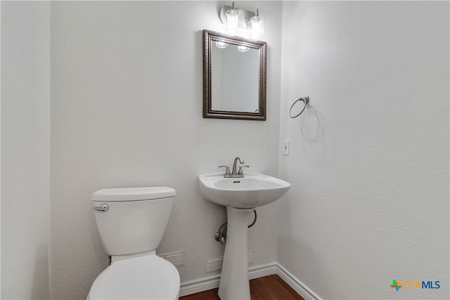 bathroom with toilet, hardwood / wood-style flooring, and sink