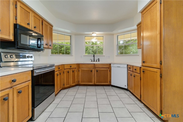 kitchen featuring a wealth of natural light, light tile patterned floors, white dishwasher, and electric stove