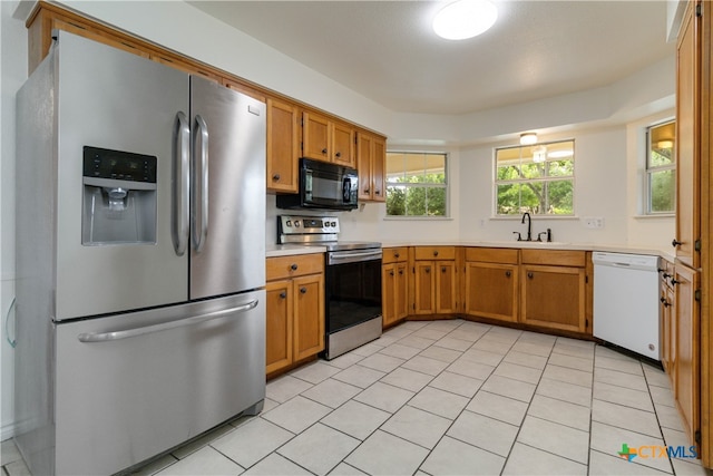 kitchen with stainless steel appliances, light tile patterned floors, and sink