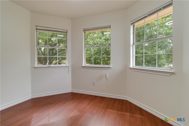 empty room featuring hardwood / wood-style flooring and a healthy amount of sunlight