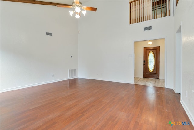 entrance foyer featuring a towering ceiling, light hardwood / wood-style floors, and ceiling fan