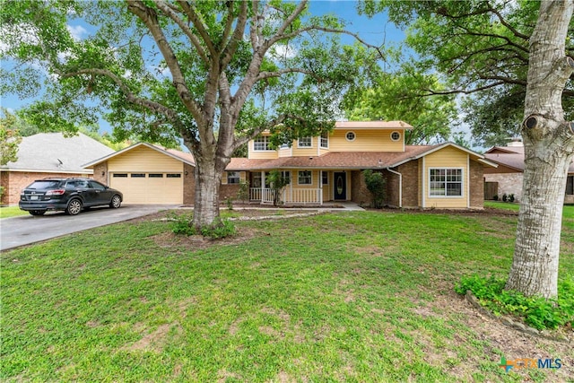 view of property with a garage, covered porch, and a front yard