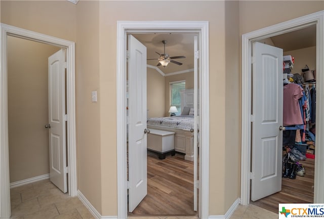 hallway with light hardwood / wood-style flooring and crown molding