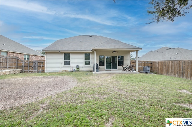 rear view of house with ceiling fan, a yard, and a patio area