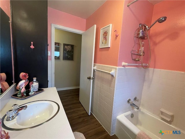 full bath with a wainscoted wall, tile walls, vanity, and wood finished floors