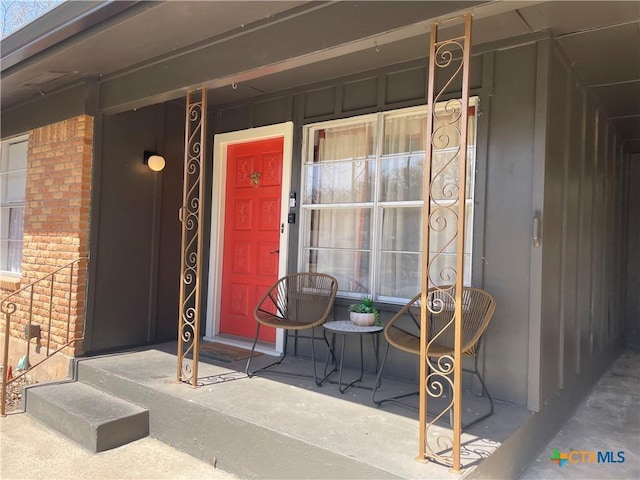 view of exterior entry with brick siding and a porch