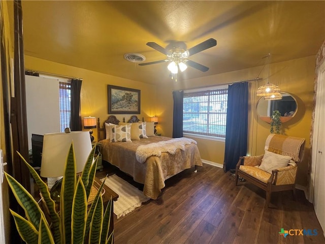 bedroom with multiple windows, dark wood-style floors, visible vents, and baseboards