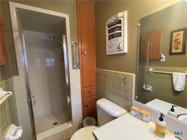 bathroom with toilet, a stall shower, tile walls, and vanity