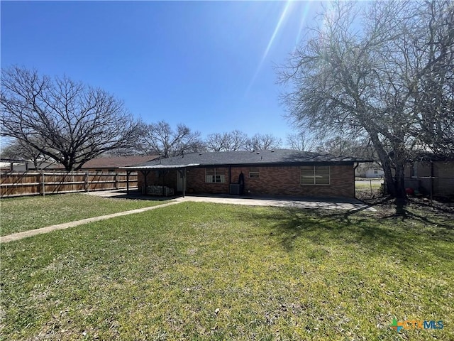 rear view of house featuring a yard, a patio, brick siding, and a fenced backyard