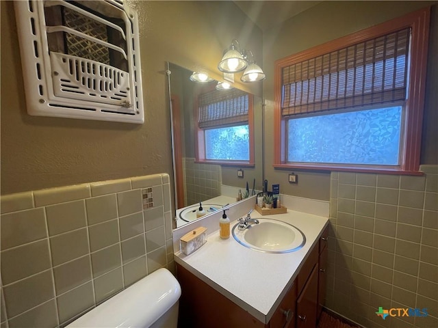 bathroom featuring vanity, tile walls, and toilet