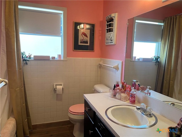 bathroom featuring tile walls, a wainscoted wall, toilet, wood finished floors, and vanity