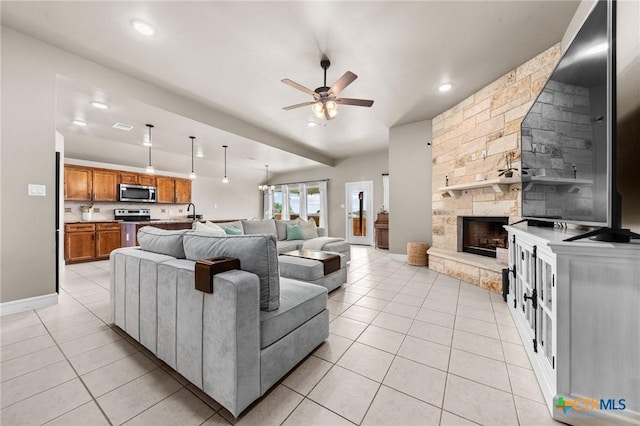 living area featuring a fireplace, baseboards, ceiling fan, and light tile patterned floors