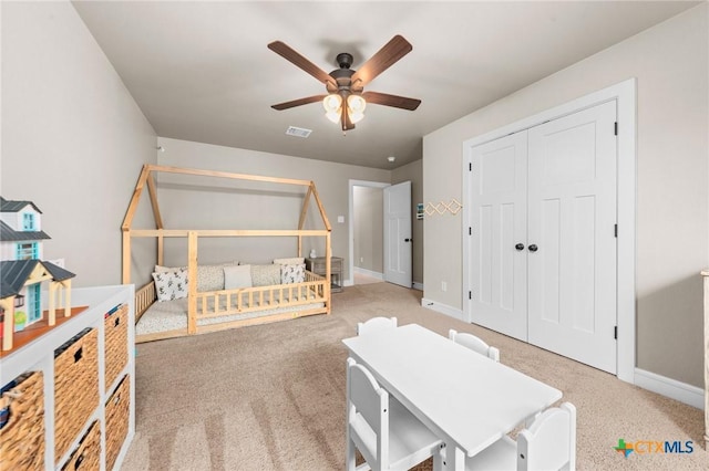 carpeted bedroom with visible vents, baseboards, a closet, and ceiling fan