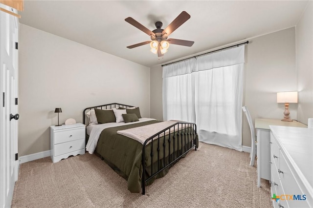 bedroom featuring light carpet, a ceiling fan, and baseboards